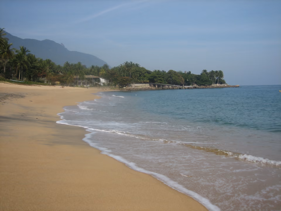 Praia da Feiticeira em Ilhabela, com mar calmo e vegetação nativa nas margens