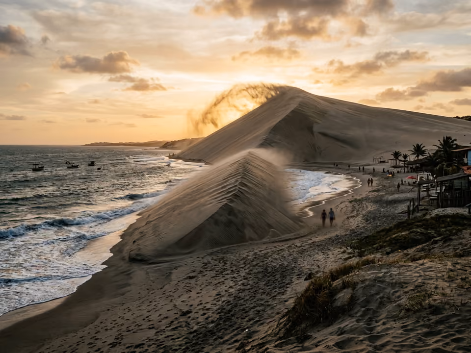Duna do Pôr do Sol vista da praia em Jericoacoara, com o vento soprando areia da crista ao entardecer