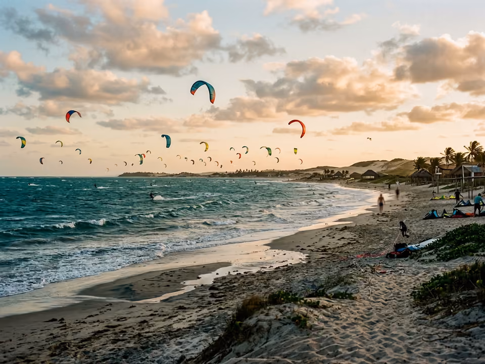 Dezenas de kites coloridos voando sobre o mar com vento constante na praia do Preá