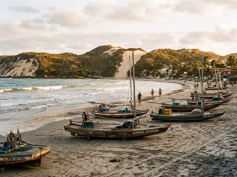 Jangadas de madeira descansando na areia da Praia de Jericoacoara com dunas e o vilarejo ao fundo