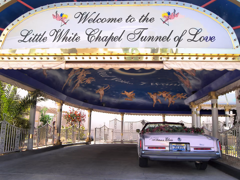 Entrada da Little White Wedding Chapel em Las Vegas, com o letreiro 'Tunnel of Love' e um carro decorado para casamento