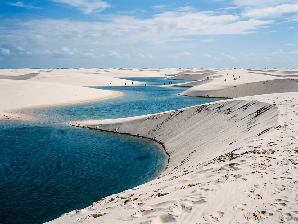 Cadeia de lagoas azuis entre dunas brancas no circuito da Lagoa Azul, com banhistas ao longe