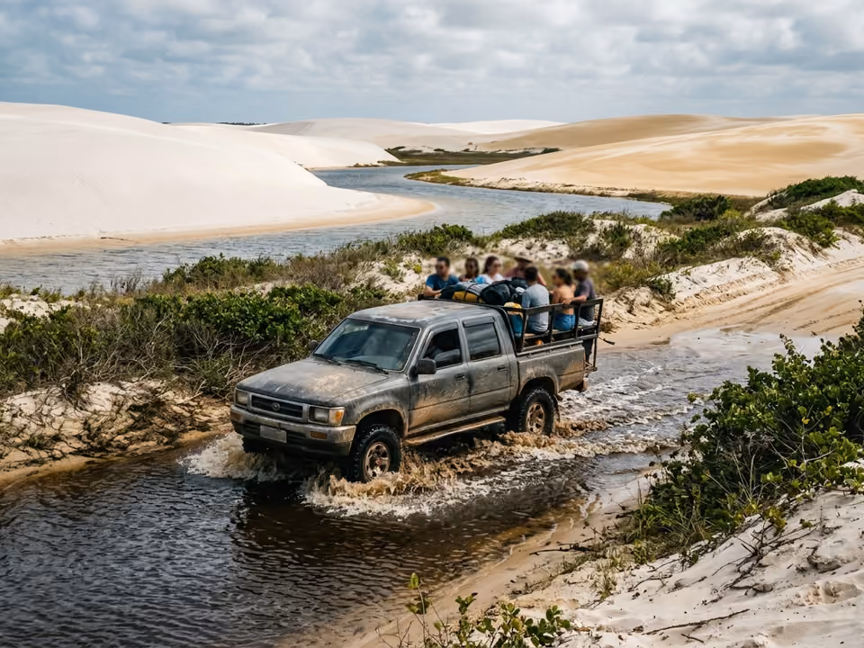 Caminhonete 4x4 cruzando trilha alagada de areia entre dunas e vegetação rasteira