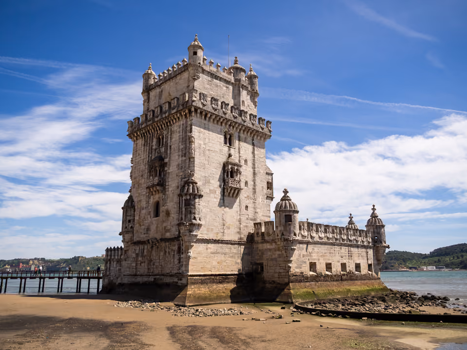 Torre de Belém, fortaleza manuelina de pedra clara à beira do Rio Tejo, com o baluarte à frente e a passarela de acesso à esquerda