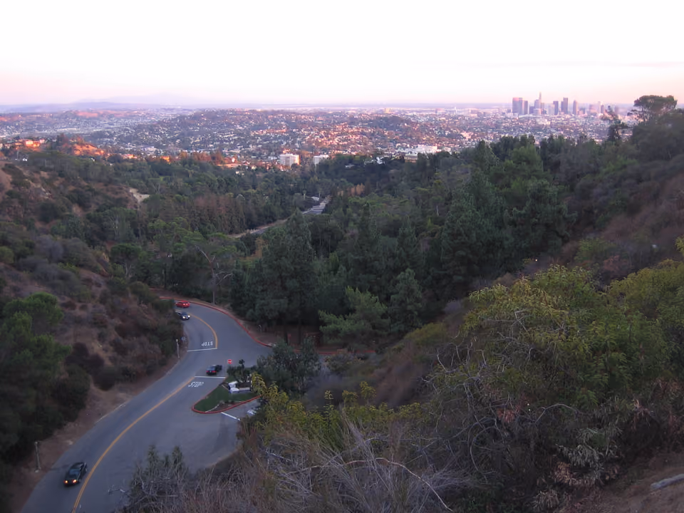 Trilha de caminhada em Griffith Park, Los Angeles, com vegetação seca típica da Califórnia e vista da cidade ao fundo