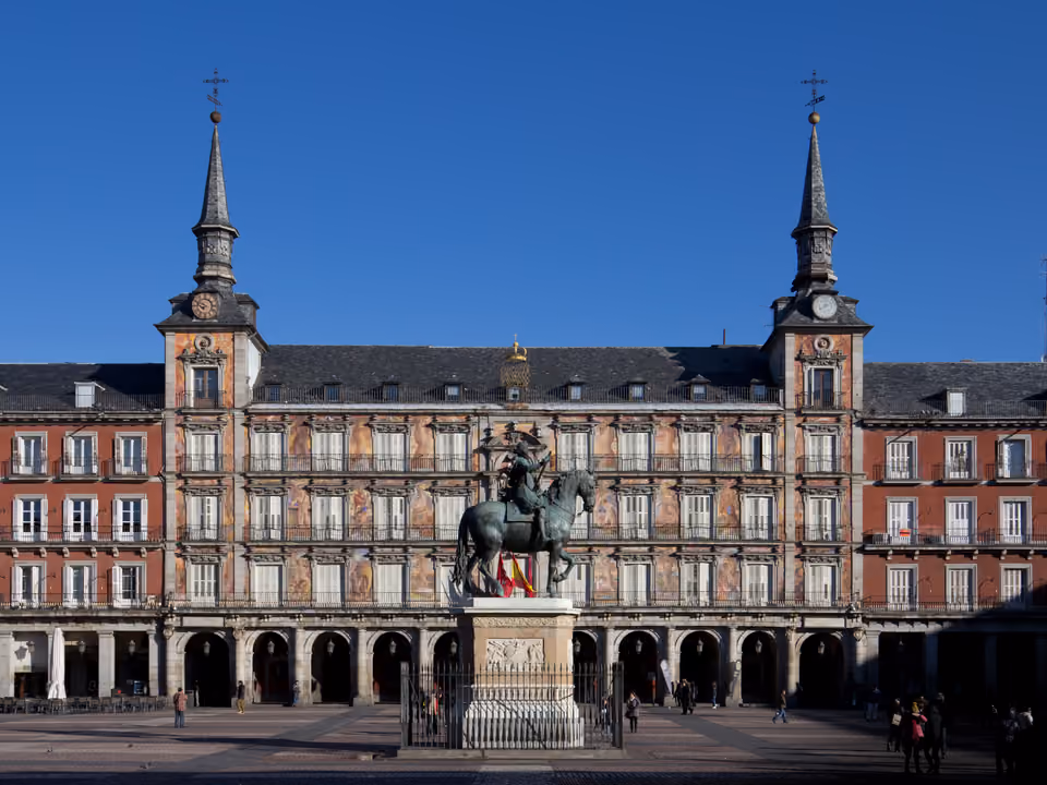 Plaza Mayor de Madri: a Casa de la Panadería afrescada com suas duas torres, a estátua equestre de Felipe III ao centro e a arcada de fachadas vermelhas ao redor