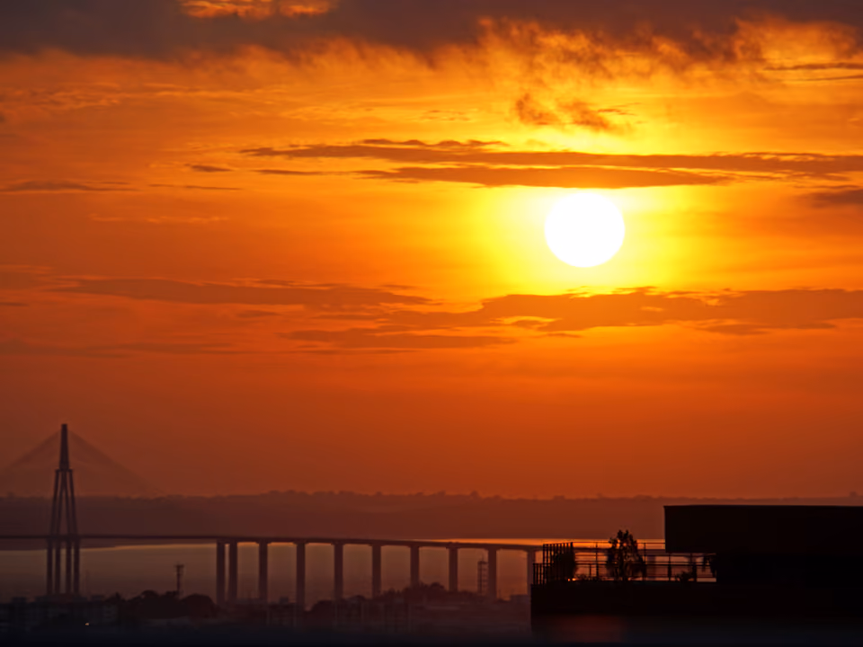 Pôr do sol alaranjado sobre o Rio Negro em Manaus, com a silhueta da ponte ao fundo