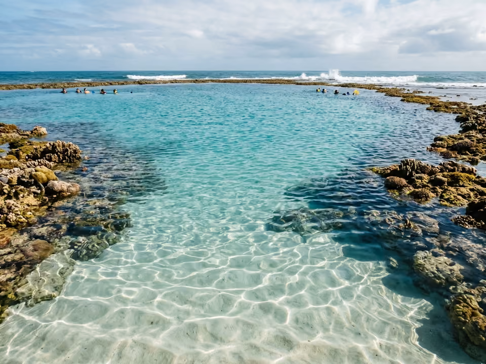 Piscinas naturais dos Galés em alto-mar, com banhistas de snorkel sobre o fundo de areia branca