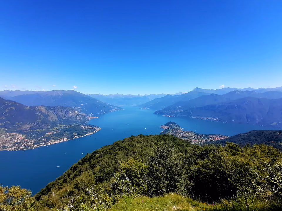 Vista panorâmica do Lago de Como do alto de uma montanha, com a bifurcação em Y do lago, o promontório de Bellagio ao centro e os Alpes ao redor
