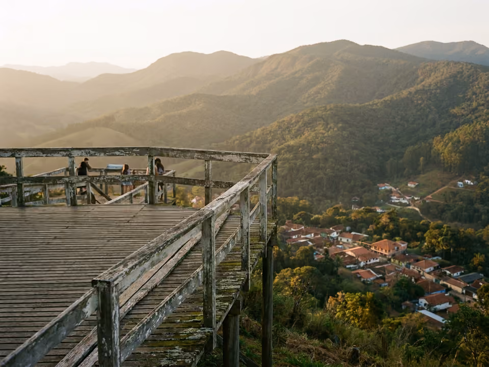 Deck panorâmico de madeira no alto da colina com vista 360° das montanhas e do vilarejo
