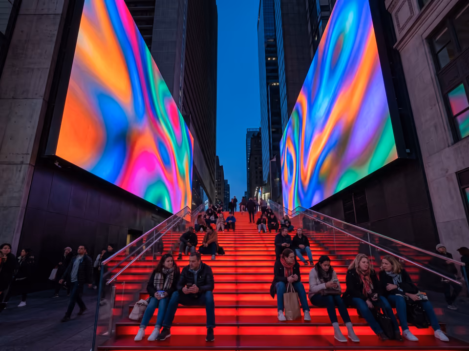 Escadaria vermelha da TKTS em Times Square, com telas gigantes de luz colorida ao entardecer