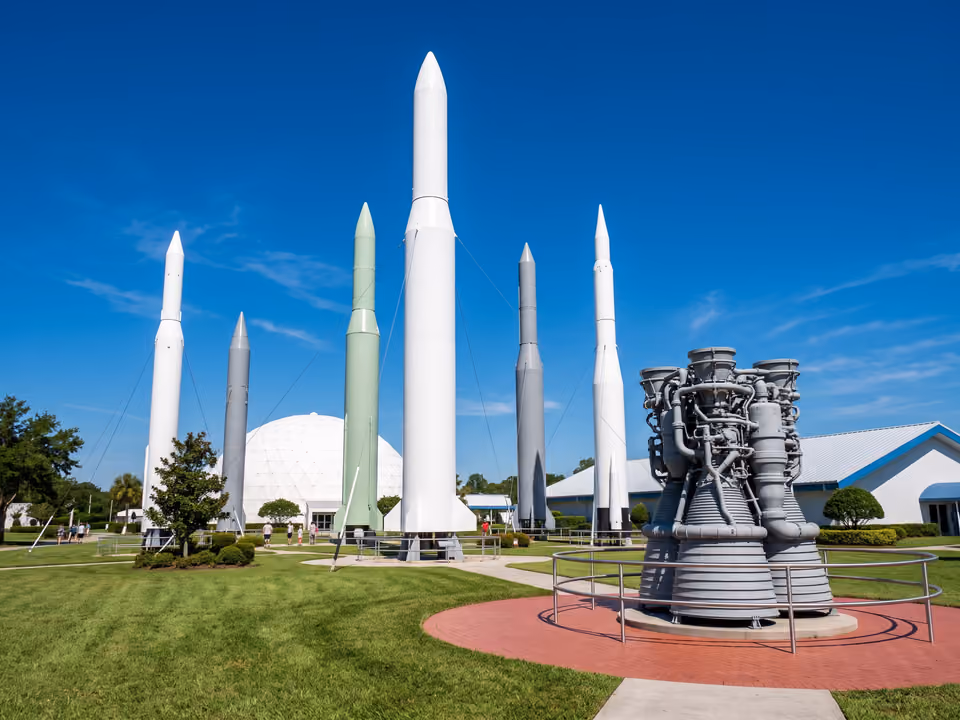 Jardim de foguetes do Kennedy Space Center Visitor Complex, com réplicas verticais e motores expostos sob céu azul