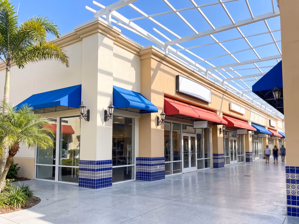 Corredor coberto de lojas do outlet em Orlando, com toldos azuis e vermelhos sob treliça branca