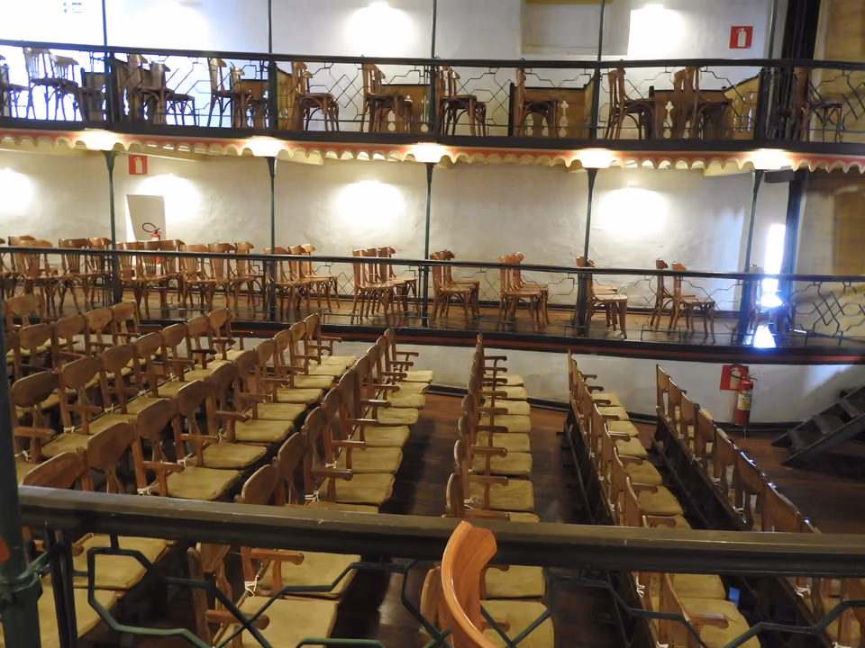 Interior do Teatro Municipal de Ouro Preto, com dois níveis de camarotes de madeira e ferro forjado sobre a plateia de cadeiras estofadas