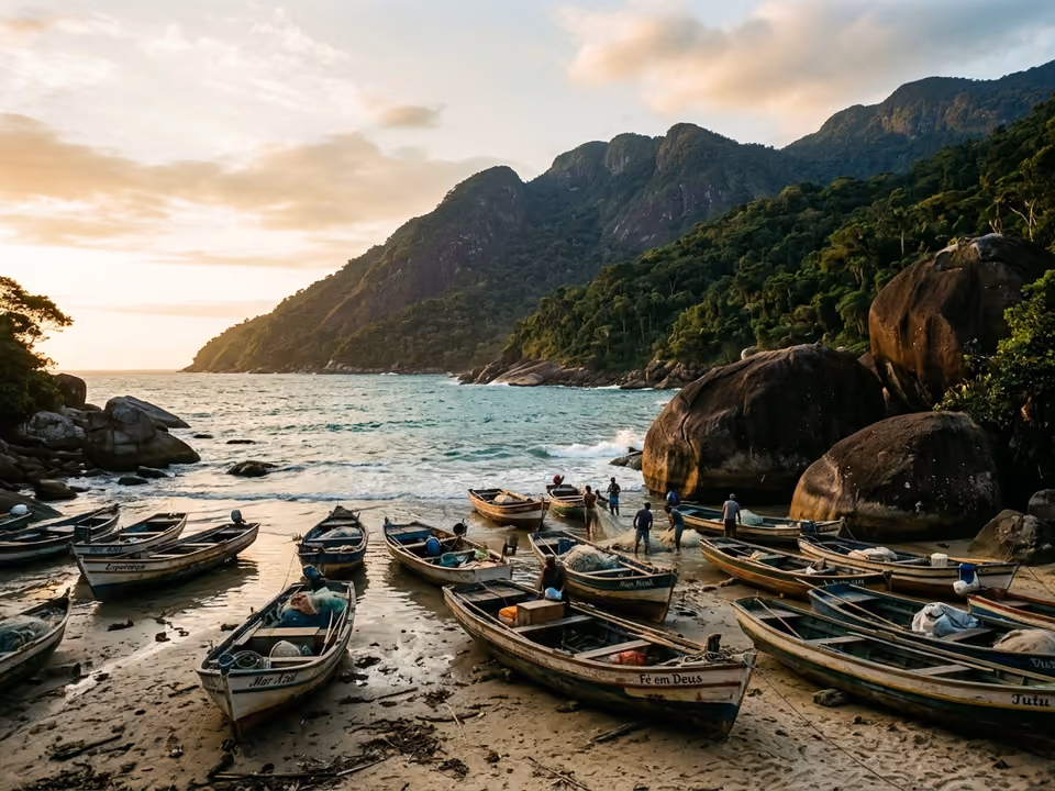 Praia da vila de Trindade com barcos de pesca, pedras arredondadas e montanhas de mata caindo no mar