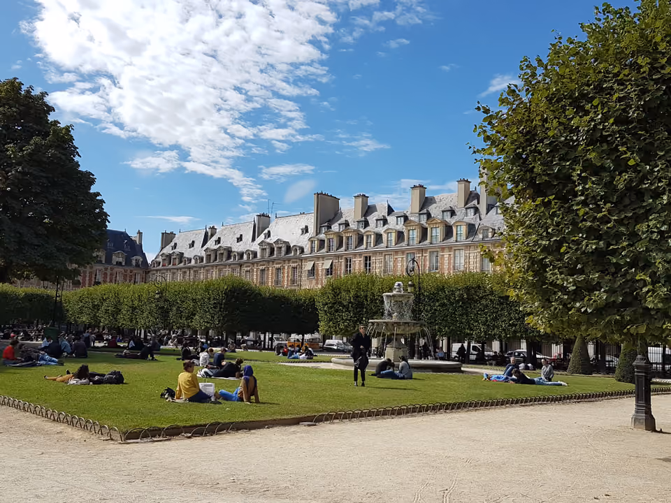 Pavilhões de tijolo vermelho com telhado de ardósia da Place des Vosges, no Marais, e o jardim central com gramados e fonte