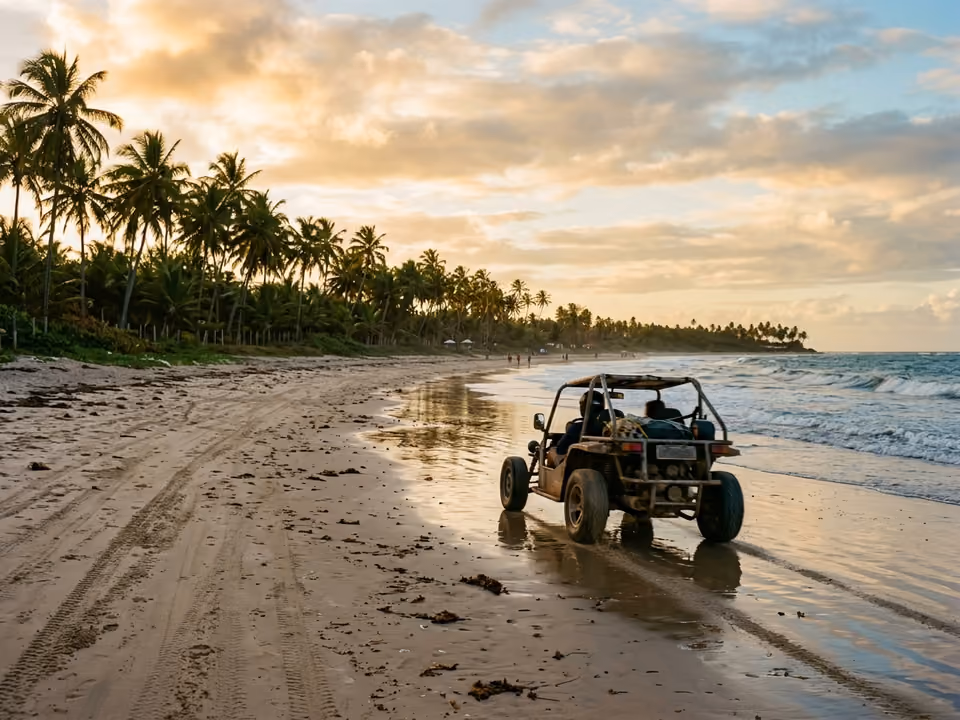 Buggy percorrendo a areia molhada de praia comprida com coqueiral