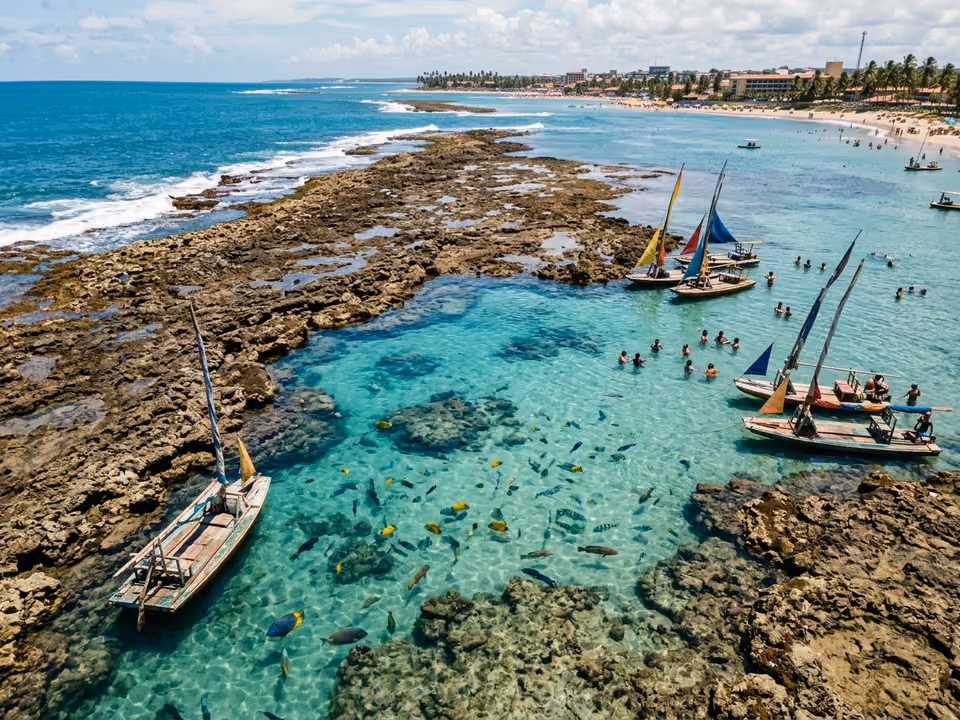 Piscinas naturais sobre os recifes na maré baixa vistas do alto, com jangadas e peixes na água clara