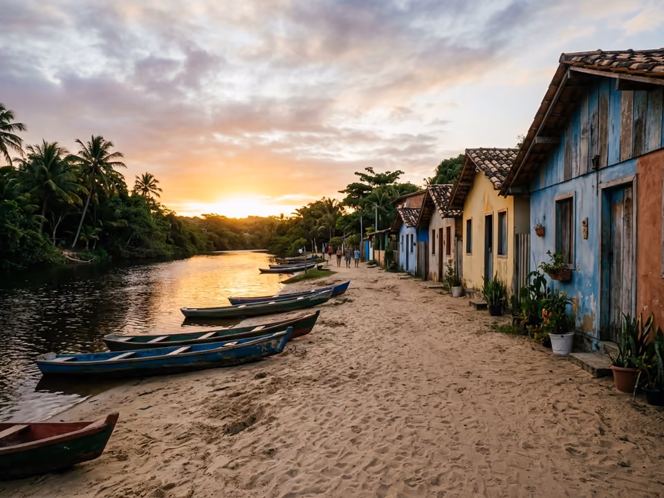Ruas de areia de Caraíva ao pôr do sol, com casas simples coloridas e canoas na margem do rio