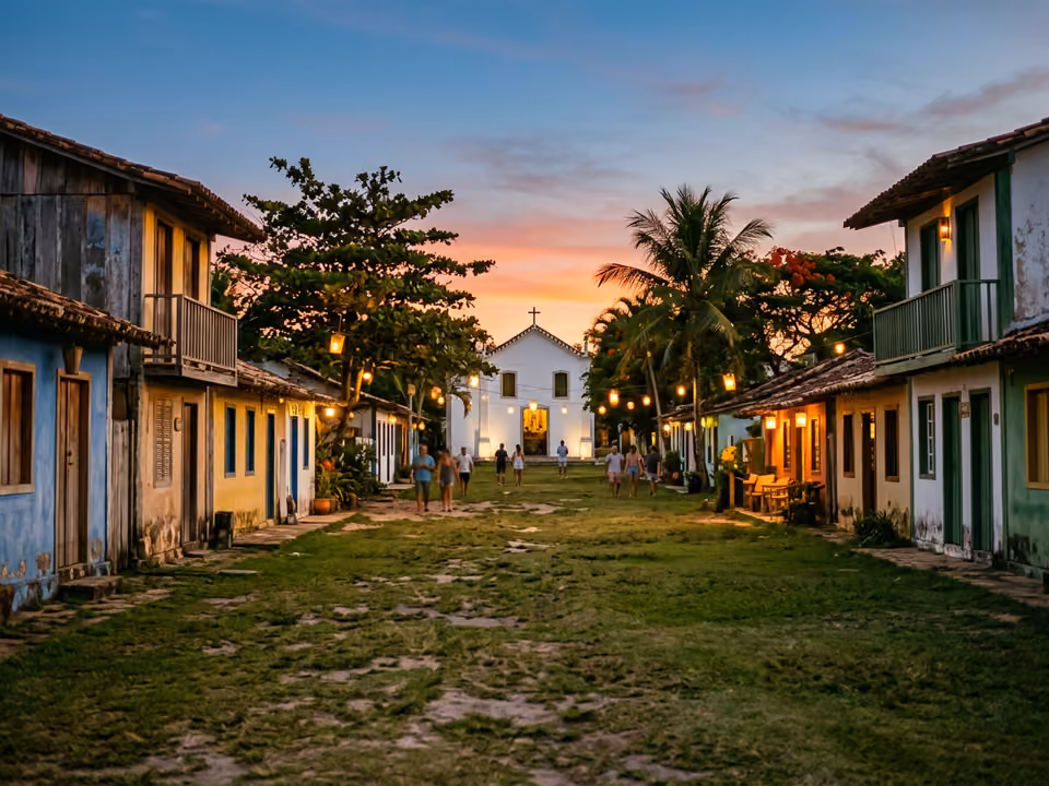 Quadrado de Trancoso ao anoitecer: gramado comprido entre casinhas coloridas e a igrejinha branca ao fundo