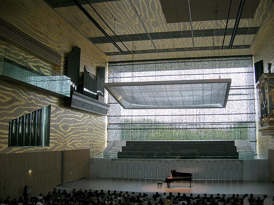 Sala de concertos principal da Casa da Música em Porto, com o piano de cauda no palco e a parede de vidro corrugado ao fundo