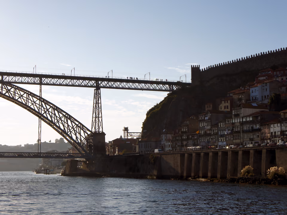 Barco turístico navegando pelo rio Douro em Porto, com várias pontes da cidade visíveis ao longo do percurso
