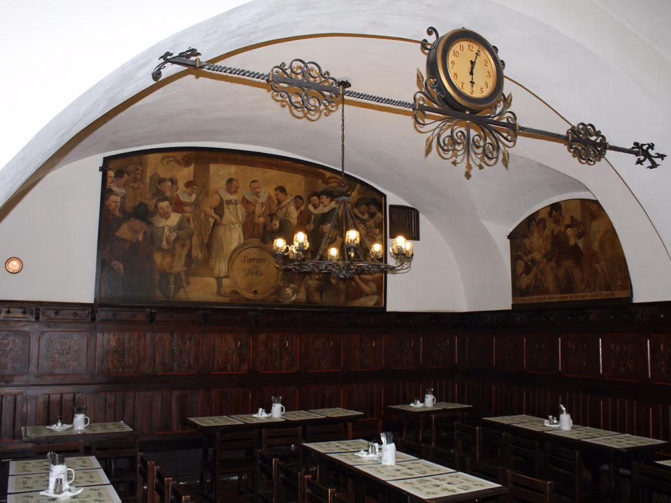 Interior da cervejaria histórica U Fleku em Praga, com mesas de madeira longas e o salão decorado em estilo tradicional tcheco