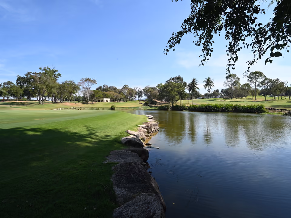Campo de golfe tropical com fairway emoldurado por árvores e um espelho d'água