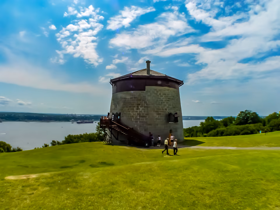 Torre Martello histórica no meio do gramado das Plaines d'Abraham, em Quebec, com o rio ao fundo