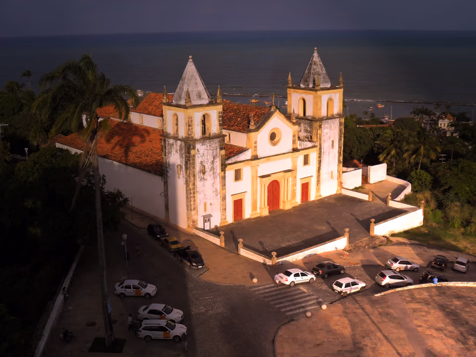 Alto da Sé em Olinda ao entardecer, com a Catedral no alto do morro, os telhados coloniais ao redor e o mar ao fundo