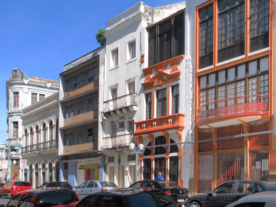 Rua do Bom Jesus em Recife, ladeada por sobrados coloniais coloridos em estilo eclético, com o calçamento de pedra e faixas coloridas suspensas