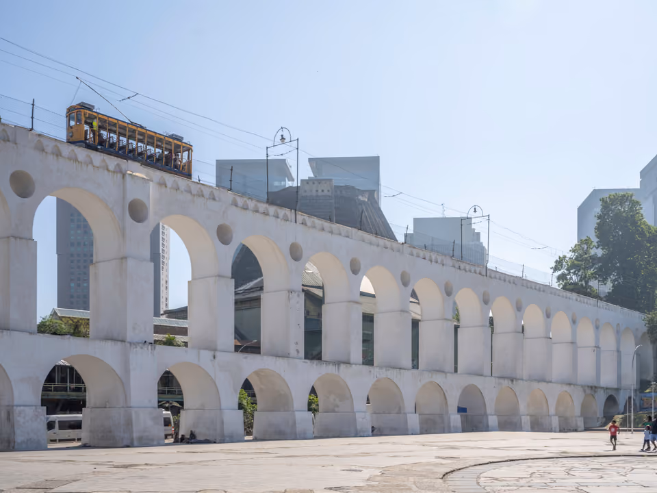 Os Arcos da Lapa, o antigo aqueduto da Carioca de dois níveis de arcos brancos no Rio de Janeiro, com o bonde amarelo de Santa Teresa cruzando por cima