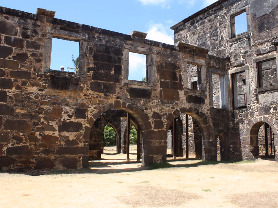 Ruínas do Castelo Garcia d'Ávila, do século XVI, na Praia do Forte, litoral norte da Bahia — paredes de pedra com janelas vazias e uma arcada, em torno de um pátio gramado