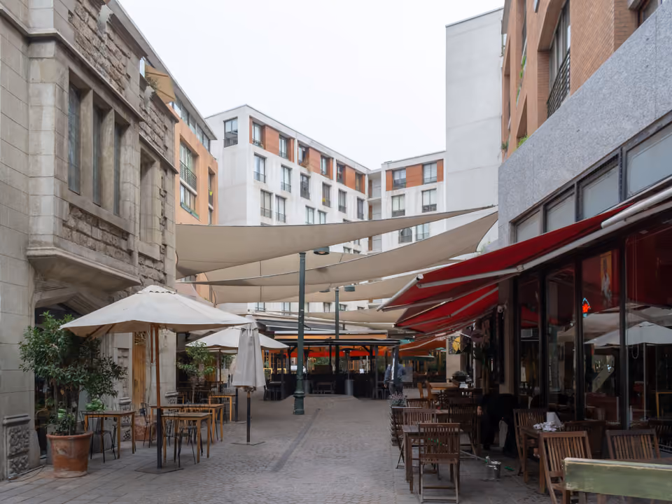 Paseo Barrio Lastarria em Santiago, passagem de paralelepípedo com mesas de café e restaurante e toldos esticados entre os prédios