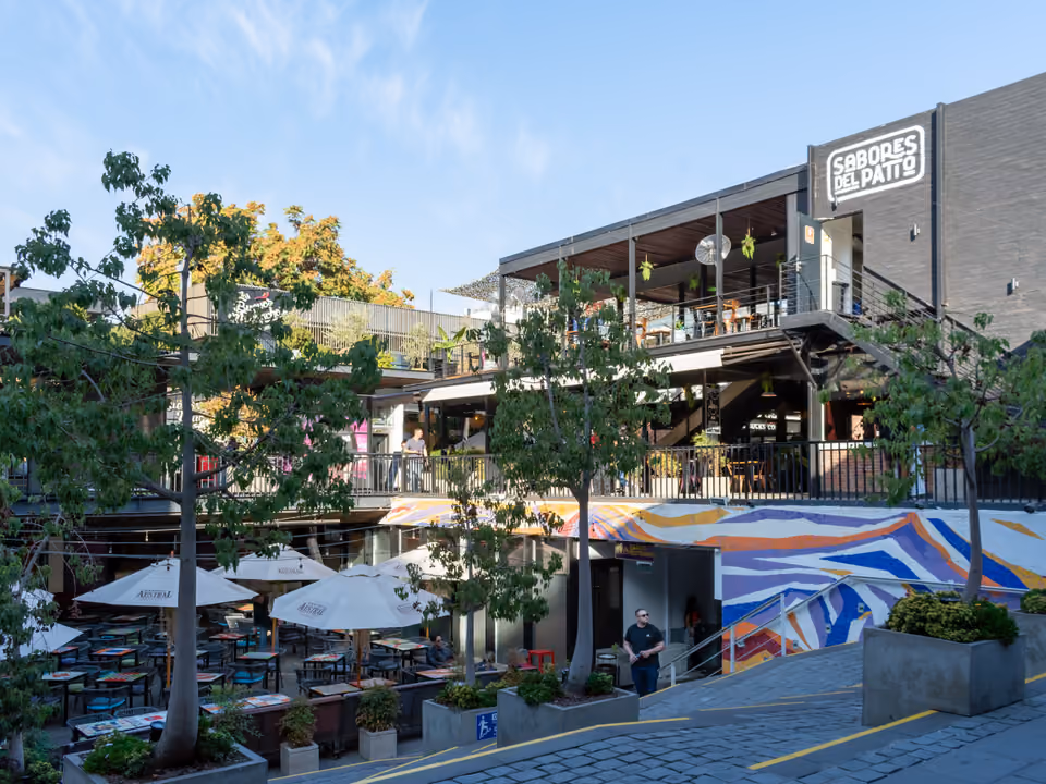 Patio Bellavista em Santiago, pátio de restaurantes em dois níveis com terraços, guarda-sóis e um mural colorido, ao pé do Cerro San Cristóbal
