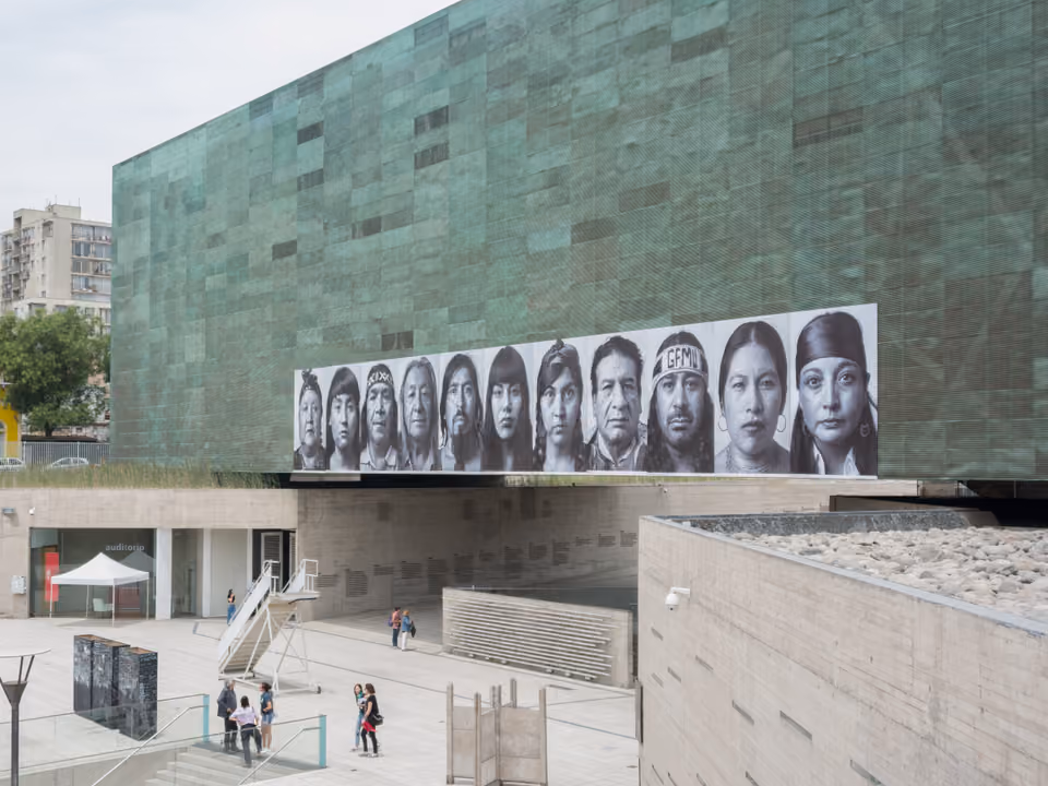 Museo de la Memoria y los Derechos Humanos em Santiago, o prédio revestido de cobre esverdeado suspenso sobre a praça, com um mural de retratos na fachada