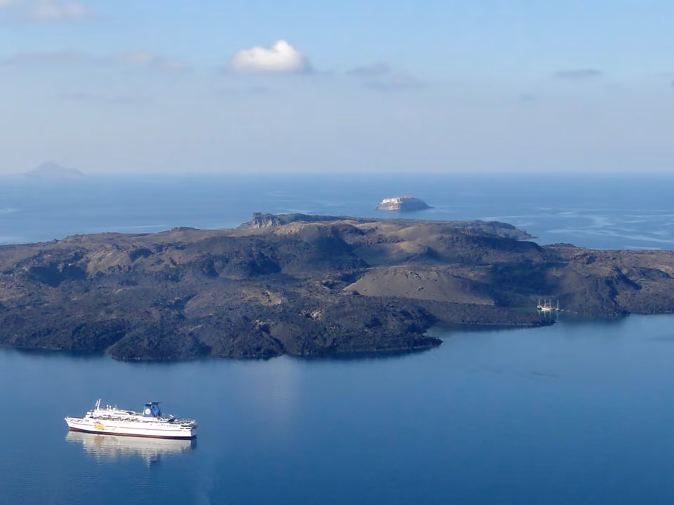 Vista aérea da caldeira vulcânica de Santorini, com o mar azul-escuro rodeado pelas ilhas e a ilha vulcânica Nea Kameni ao centro