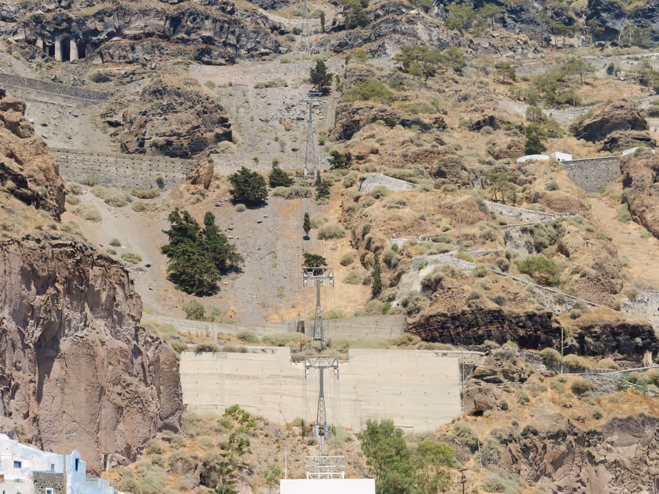Cidade de Fira em Santorini, construída na borda da caldeira, com o teleférico visível descendo até o porto