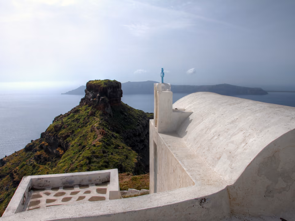Vila de Imerovigli em Santorini, com casas brancas na borda da caldeira e a formação rochosa Skaros Rock ao fundo