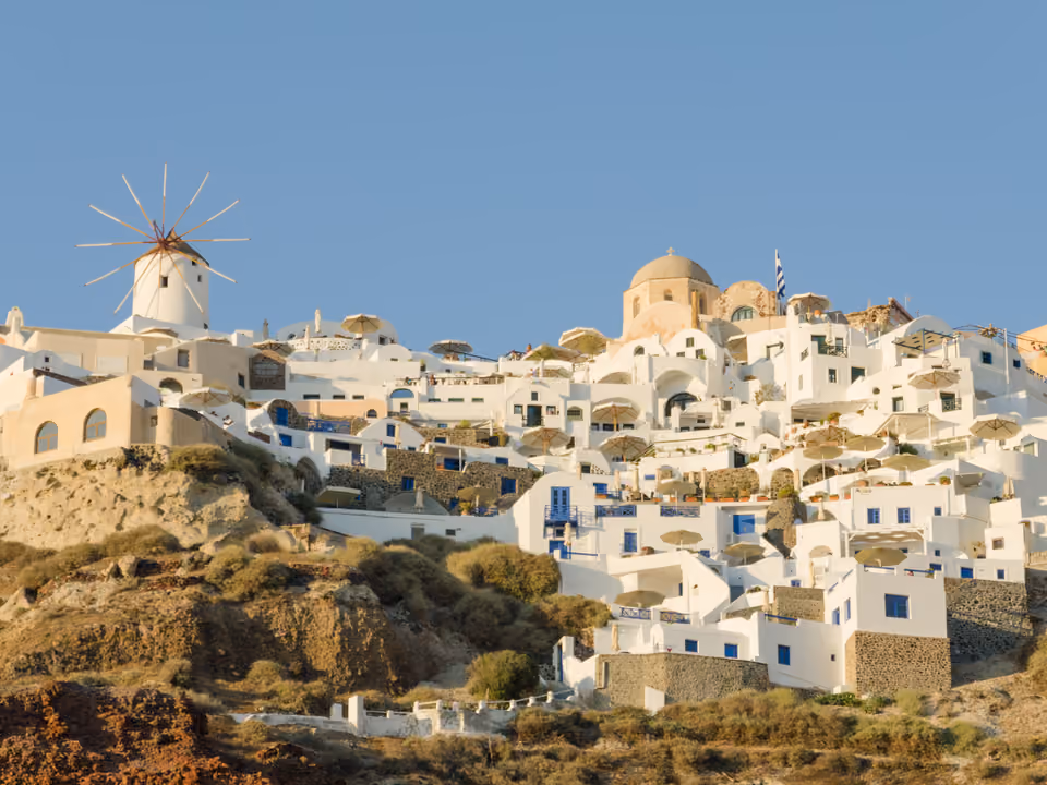 Vila de Oia em Santorini, com casas brancas e cúpulas azuis construídas na borda da caldeira vulcânica