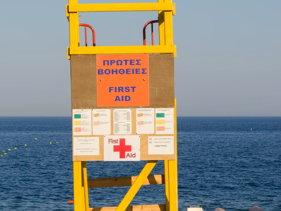 Praia de areia preta vulcânica em Perissa, Santorini, com espreguiçadeiras alinhadas à beira do mar Egeu