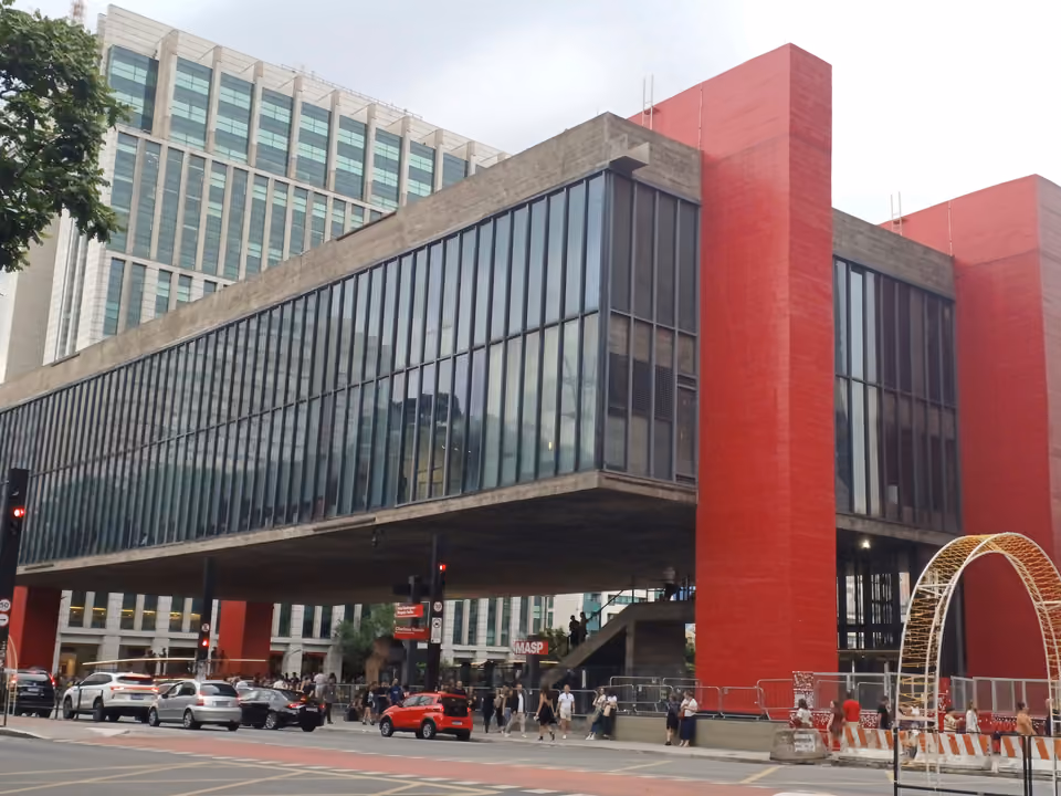 O prédio do MASP na Avenida Paulista, a caixa de concreto e vidro suspensa pelas pilastras vermelhas sobre o vão livre, com o letreiro do museu na base
