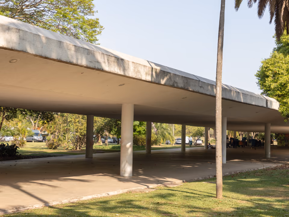 A marquise de concreto do Parque Ibirapuera, em São Paulo, a laje branca sobre pilares que liga os pavilhões modernistas, com gramado e árvores em volta