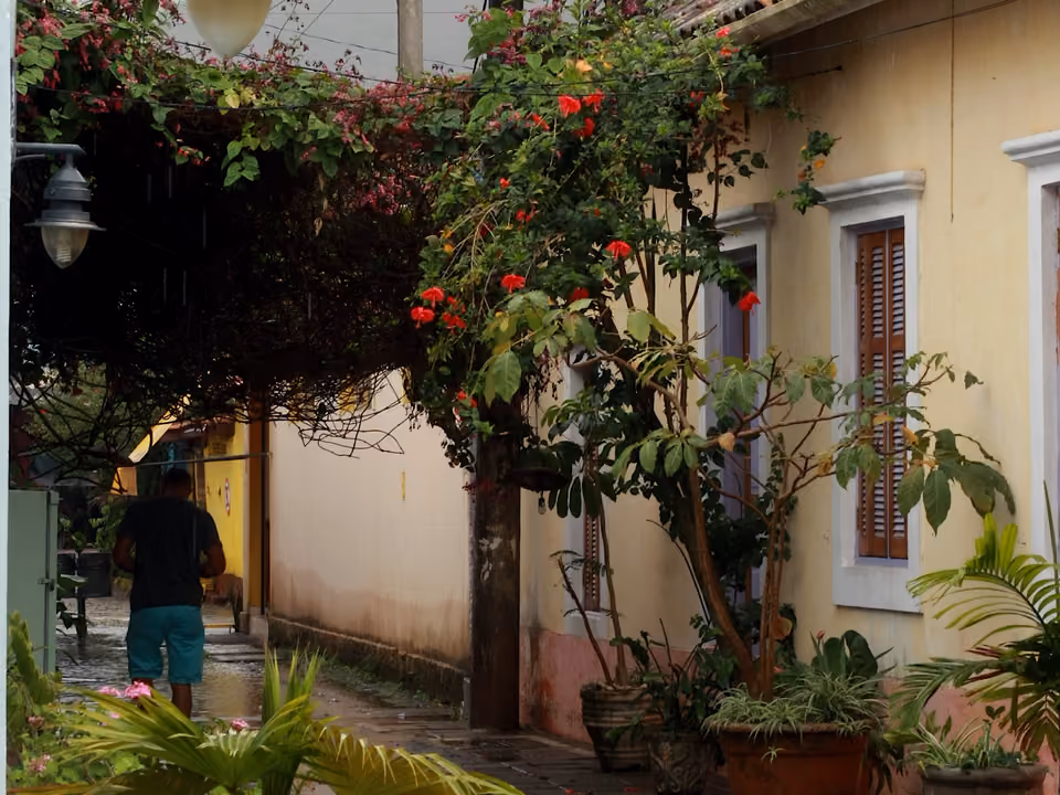 Casario colonial amarelo coberto de flores, com fiação aparente, no centro histórico de São Sebastião