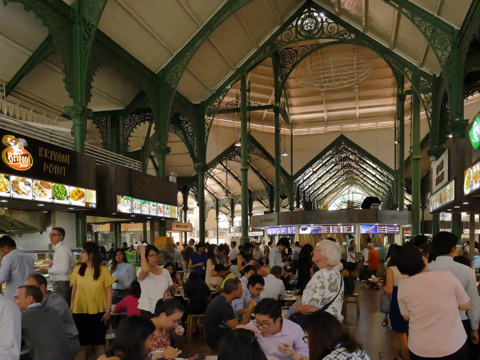 Interior de um hawker center em Singapura, com várias barracas de comida e mesas cheias