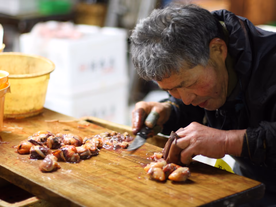 Vendedor preparando fruto do mar fresco numa banca do mercado de peixe de Tóquio