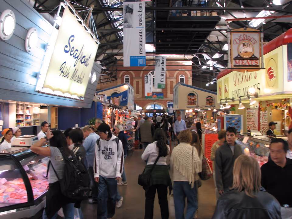 Interior do St. Lawrence Market em Toronto, com barracas de comida e produto fresco sob a estrutura histórica de tijolo