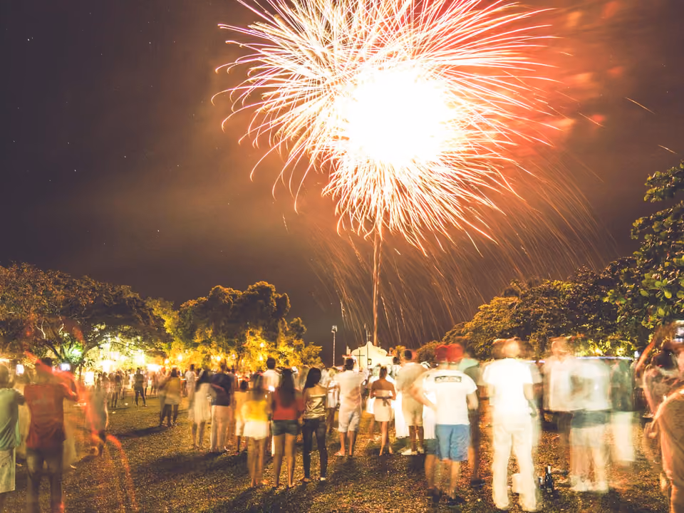 Show de fogos de artifício de Réveillon sobre o Quadrado de Trancoso, com pessoas reunidas no gramado à noite