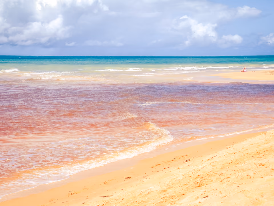 Praia baiana com água em tons avermelhados, ilustrativa — não é a foto do Rio Verde em si