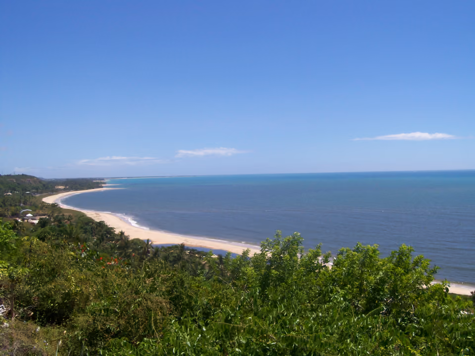 Vista elevada da costa de Trancoso, com faixa de praia e vegetação nativa se estendendo ao longo do litoral